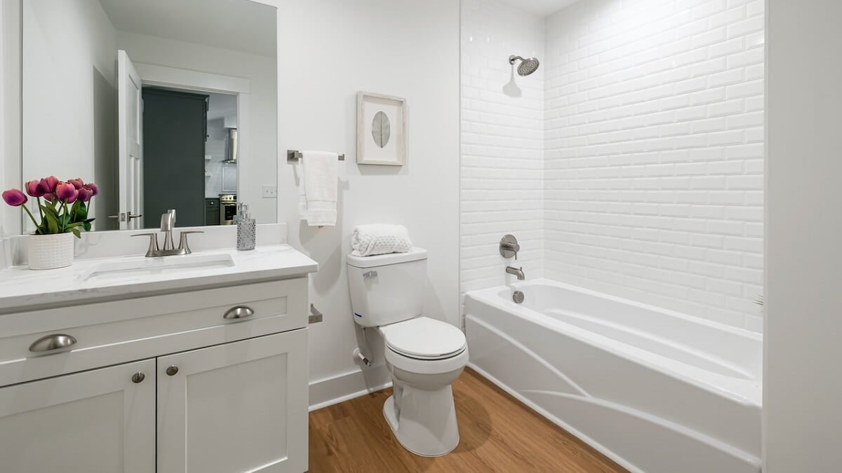 Banheiro branco, com banheira e quadro na parede