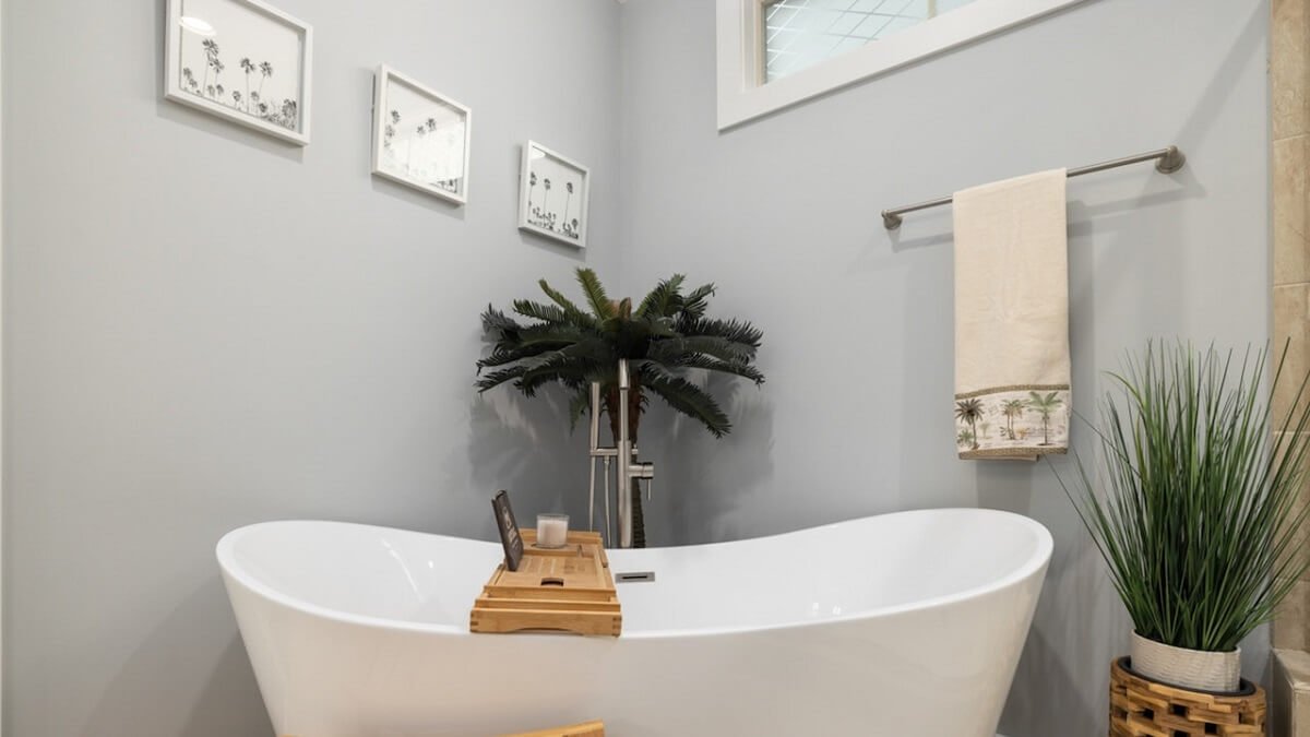 Banheiro com tons neutros, com banheira, plantas e quadros na parede