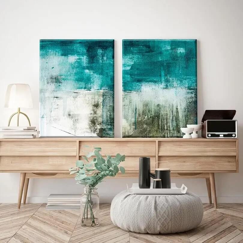 Dois quadros abstratos com tons de azul em um móvel de uma sala de estar
